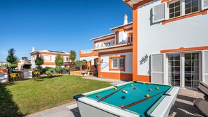 Een zwembad met een pooltafel, een barbecue en een verzorgd gazon.
