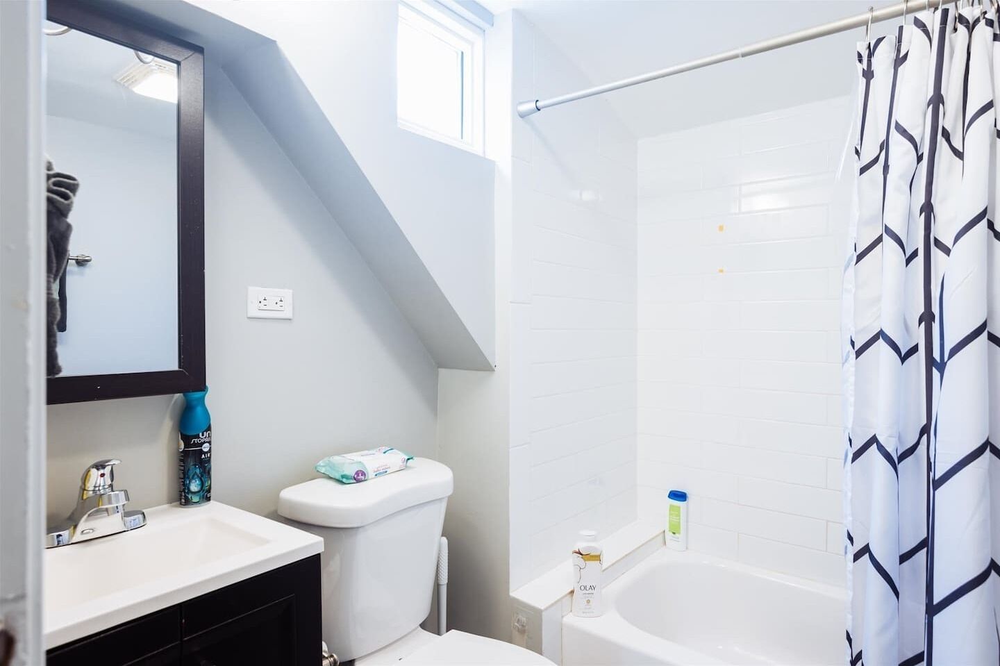 A bathroom with a white sink, mirror, toilet, and bathtub.