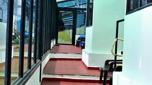Un pasillo cubierto con grandes ventanales, piso rojo y pared blanca.