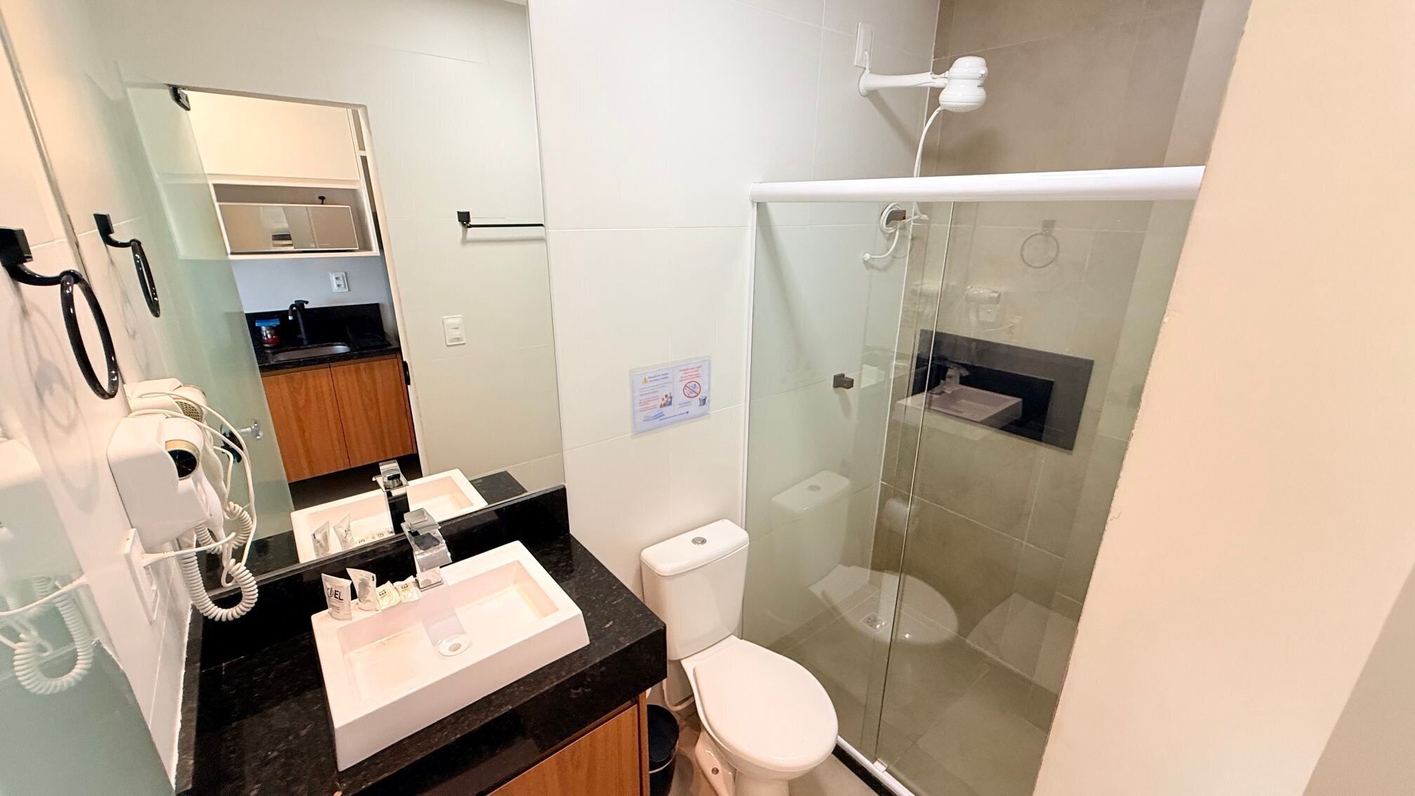 A modern bathroom with a glass-enclosed shower, a sink with toiletries, and a toilet.