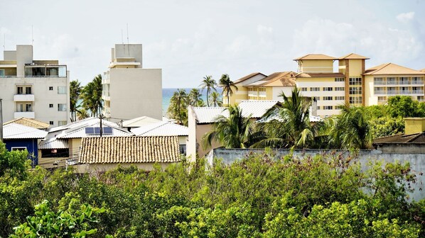 A coastal residential area with modern buildings, including a multi-story structure with balconies and a flat-roofed building with solar panels. - Stella Studio (Salvador)
