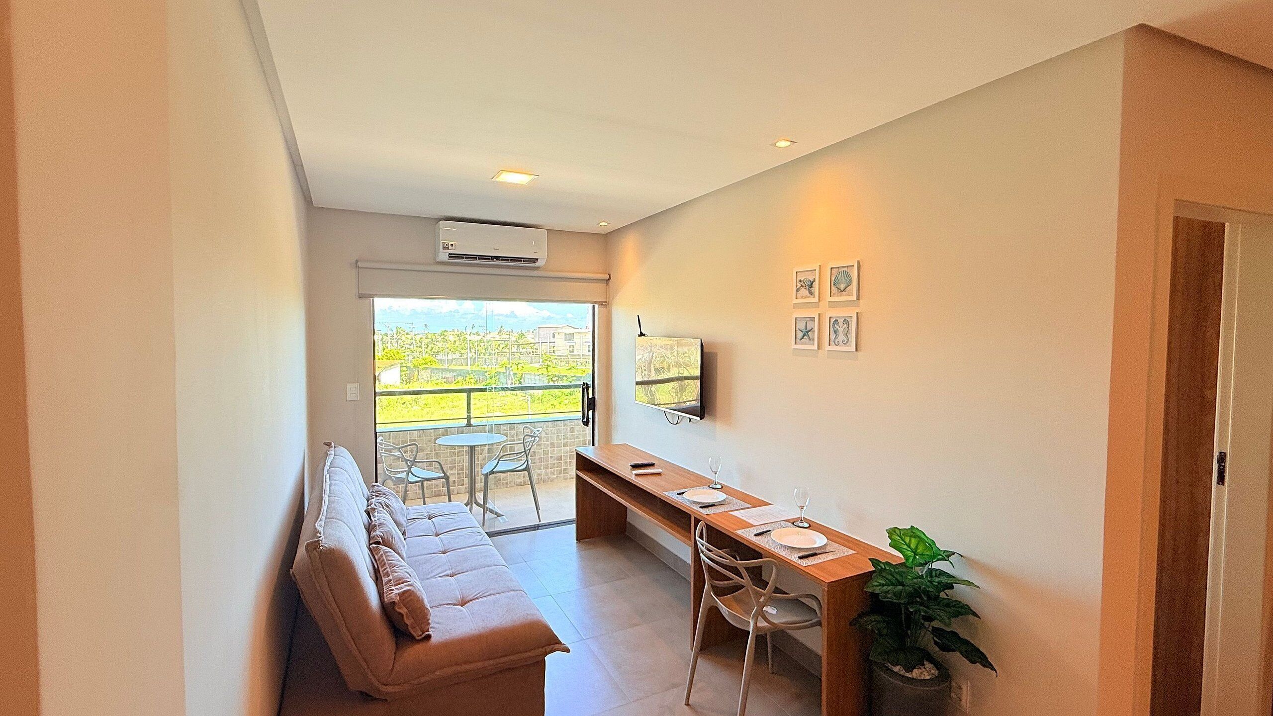 Un salon moderne comprenant un canapé, une table à manger, des chaises, un téléviseur et un balcon avec vue.