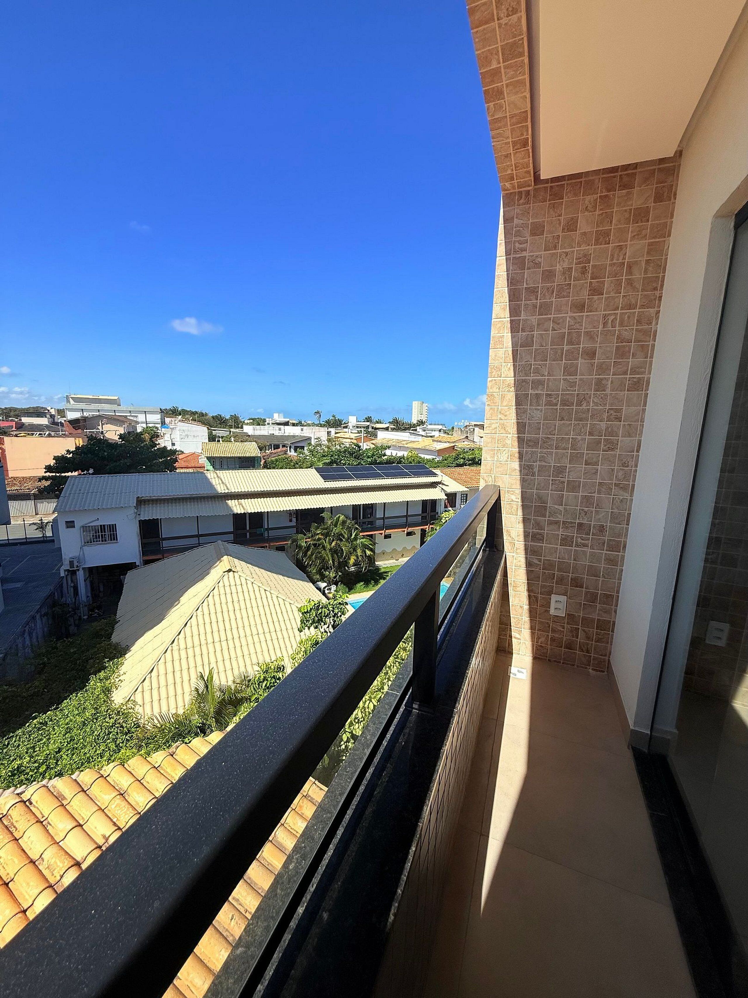 En balkon med udsigt over bybilledet, en fliseklædt væg og en dør.