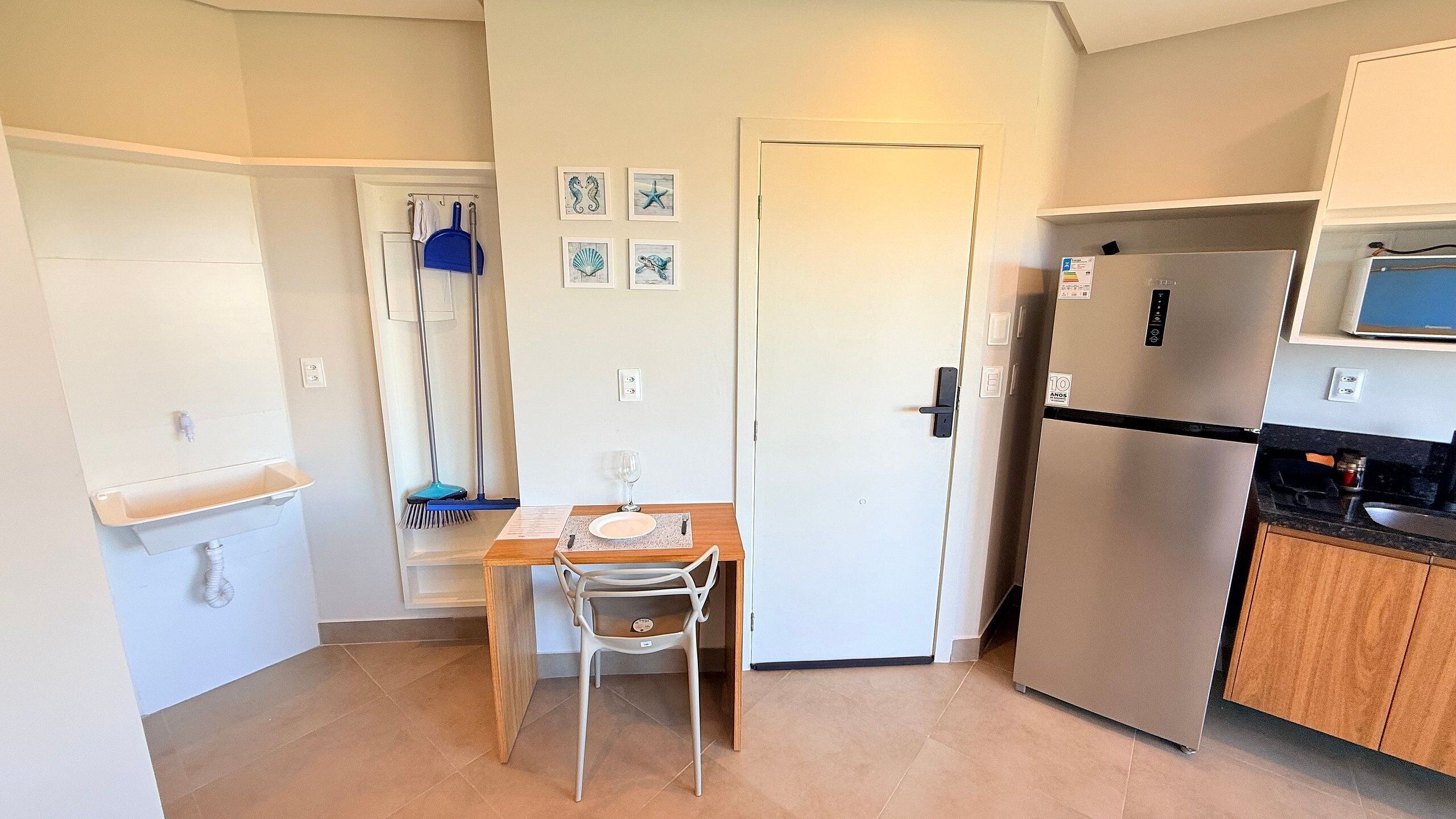 Eine kompakte Küche mit integriertem Kühlschrank, einer Mikrowelle und einem Essbereich mit Tisch und Stühlen.