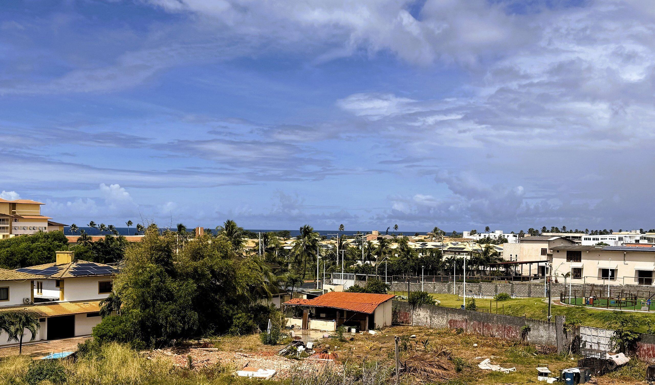 Zona residencial com casas, piscina e vista para o oceano.