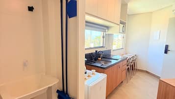 Et moderne køkken med hvide skabe, en indbygget ovn og et spiseområde med stole.