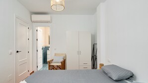 Ein Schlafzimmer mit Bett, Stuhl, Kleiderschrank und Klimaanlage.