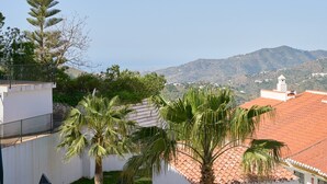 Ein Wohngebiet mit einem weißen Gebäude, Palmen und Blick auf ein Gebirge.