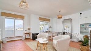 Ein modernes Wohnzimmer mit einer Couch, zwei Sesseln, einem Esstisch und einem großen Spiegel.