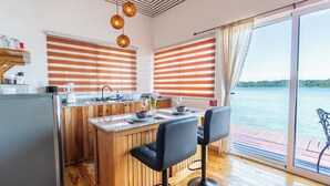A modern kitchen with wooden accents, a bar area, and large windows with blinds. - Coral Wing Casitas (Bastimentos)