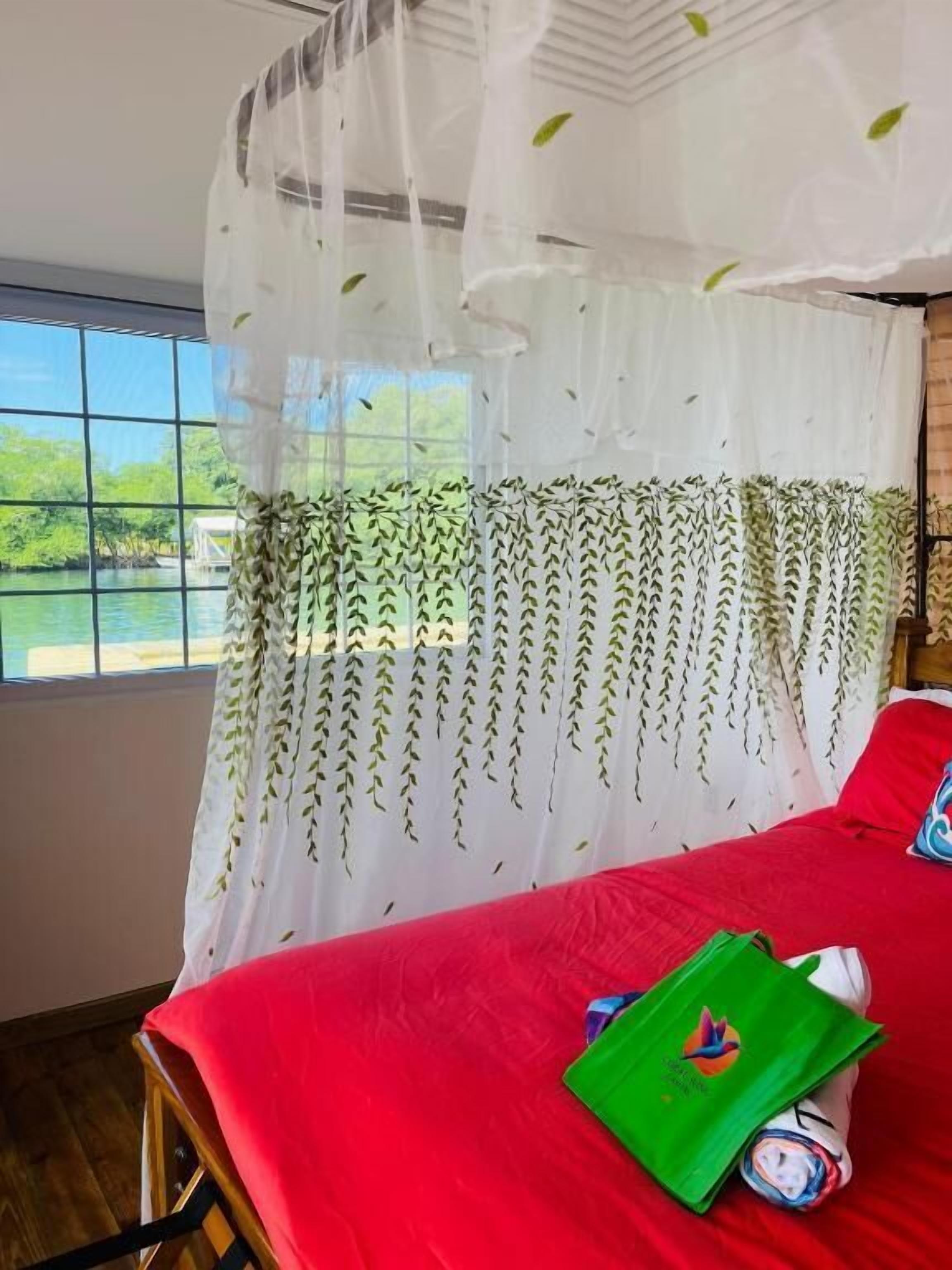 A room with a bed, a window, and a view of a body of water.