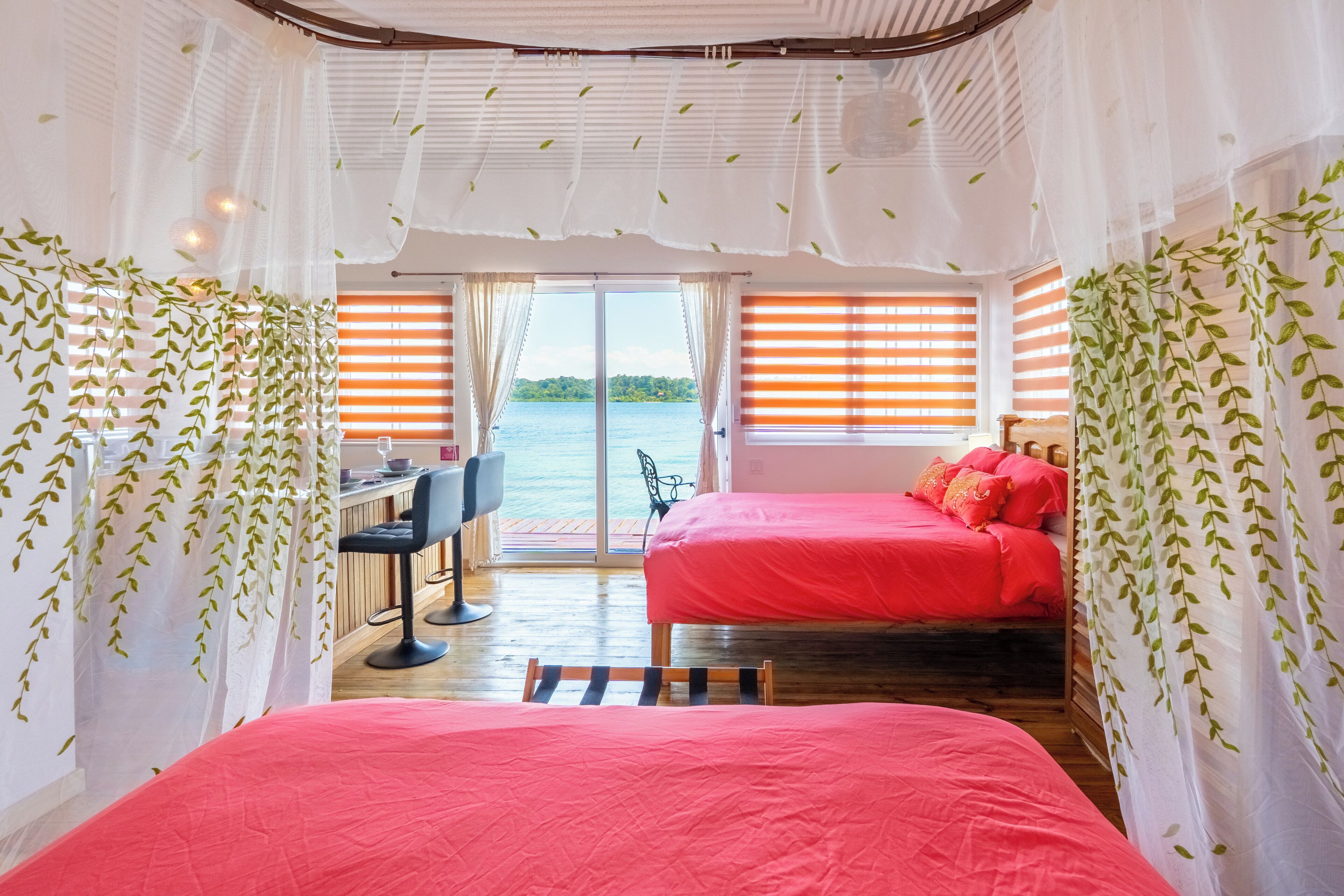 A room with two beds, a desk, and a view of the water.