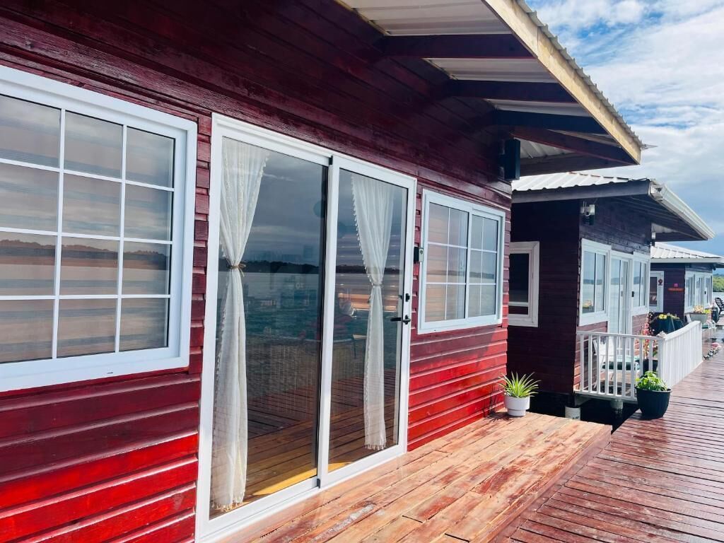 A red wooden building with large windows and a wooden deck.