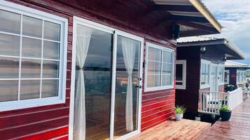 A red wooden building with large windows and a wooden deck.