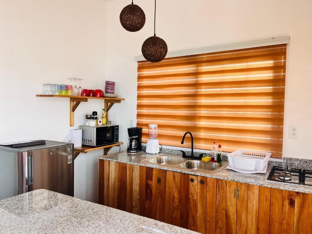 A compact kitchen with a built-in refrigerator, a sink, a stove, and wooden cabinetry.