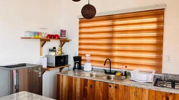 A compact kitchen with a built-in refrigerator, a sink, a stove, and wooden cabinetry.