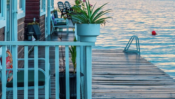 A wooden dock with chairs and potted plants, overlooking a body of water with a sunset in the background. - Coral Wing Casitas (Bastimentos)