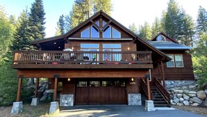 A two-story wooden cabin with a balcony, stone steps, and a garage. - Gorgeous Donner Lake 3BR + Loft Modern Home in Truckee (Truckee)