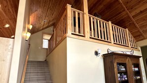 A wooden staircase leading to a balcony with a railing, a cabinet with glass doors, and a potted plant. - Gorgeous Donner Lake 3BR + Loft Modern Home in Truckee (Truckee)