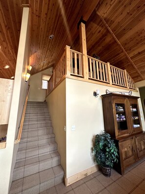 A wooden staircase leading to a balcony with a railing, a cabinet with glass doors, and a potted plant. - Gorgeous Donner Lake 3BR + Loft Modern Home in Truckee (Truckee)