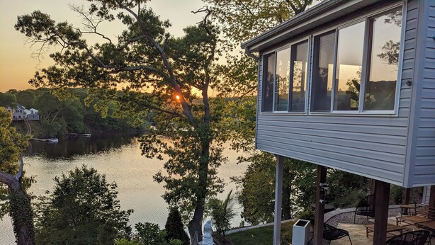 Una casa frente al lago con terraza, mobiliario exterior y vistas al lago.