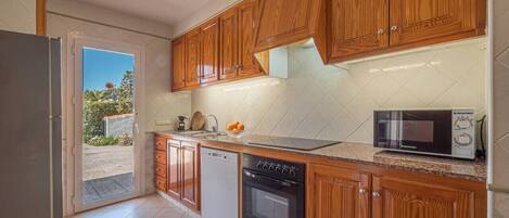 Eine Küche mit Holzausstattung, Geschirrspüler, Backofen und Mikrowelle.