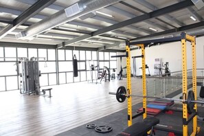 Une salle de sport équipée de matériel de musculation, d’un sac de frappe et d’appareils de cardio-training.