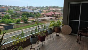 A balcony with potted plants, a chair, and a view of a residential area. - Delightful 3-bedroom apartment in welcoming Accra neighborhood (Accra)