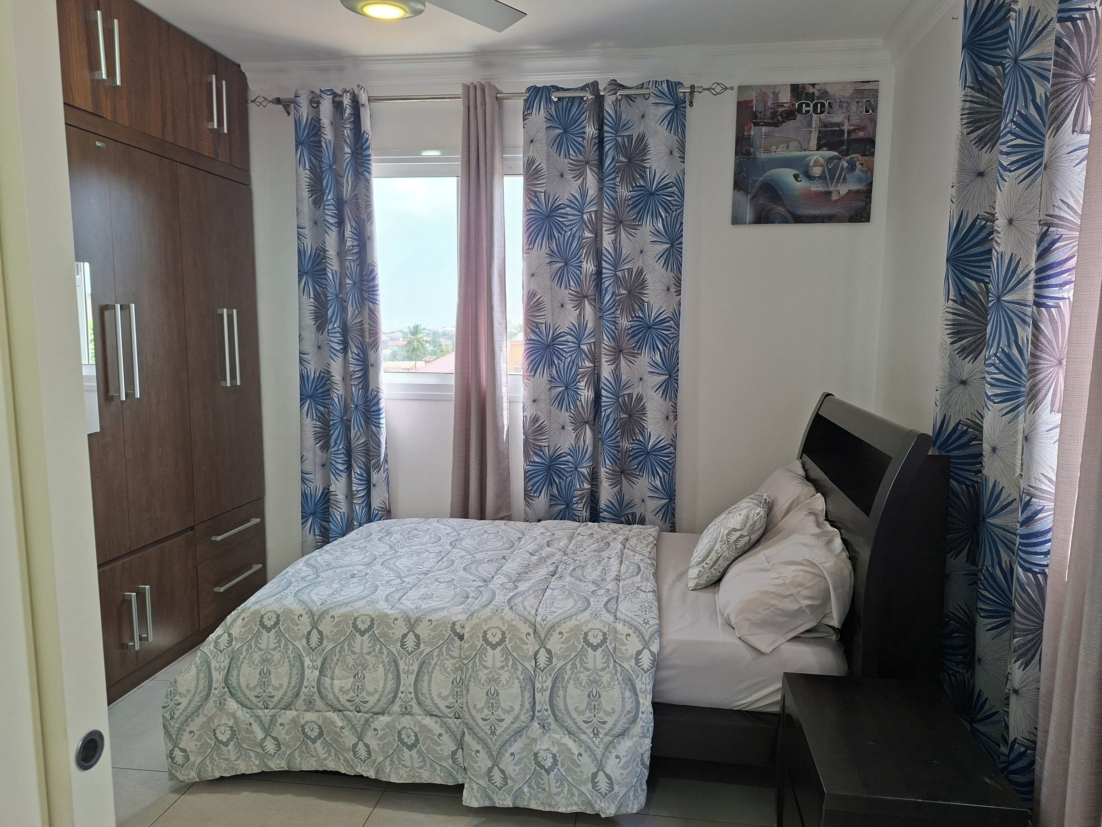 Un dormitorio con cama, armario, cortinas y un cartel en la pared.