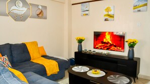 Una sala de estar moderna con sofá, mesa de centro y televisor de pantalla plana montado en la pared.