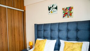 Un dormitorio con una cama grande, un armario de madera y dos cuadros en la pared.