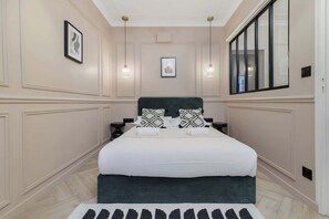 Ein Schlafzimmer mit einem großen Bett, zwei Nachttischen, einer Kopfteil und einem Fenster mit Jalousien.