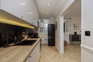 Eine moderne Küche mit einem schwarzen Kühlschrank, einer Holz Arbeitsplatte und Blick in den angrenzenden Essbereich.
