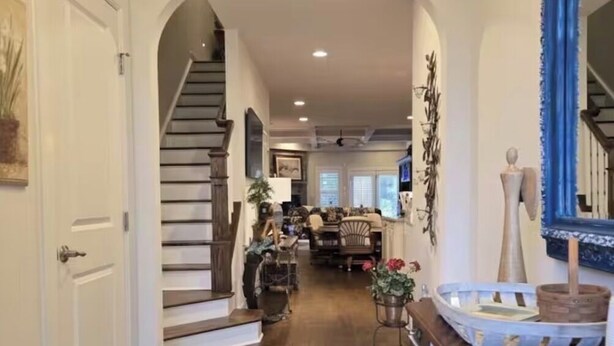A spacious hallway with a wooden floor, an arched doorway, and a staircase leading to another room.