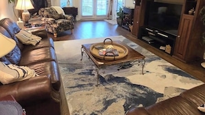A living room with a fireplace, leather sofas, a coffee table, and a TV cabinet.