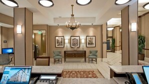 A hotel lobby with a reception desk, two armchairs, a chandelier, framed pictures on the wall, and a computer monitor. - 2 Queen Studio Near Waterfront | Free Breakfast! (Baltimore)