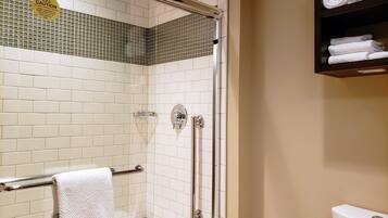 A bathroom with white tiled walls, a glass shower enclosure, a toilet, and a towel rack.
