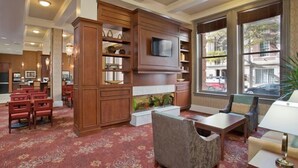 Eine Hotelhalle mit Kamin, Sitzgruppe und einem an einem Holzkabinett befestigten Fernseher.