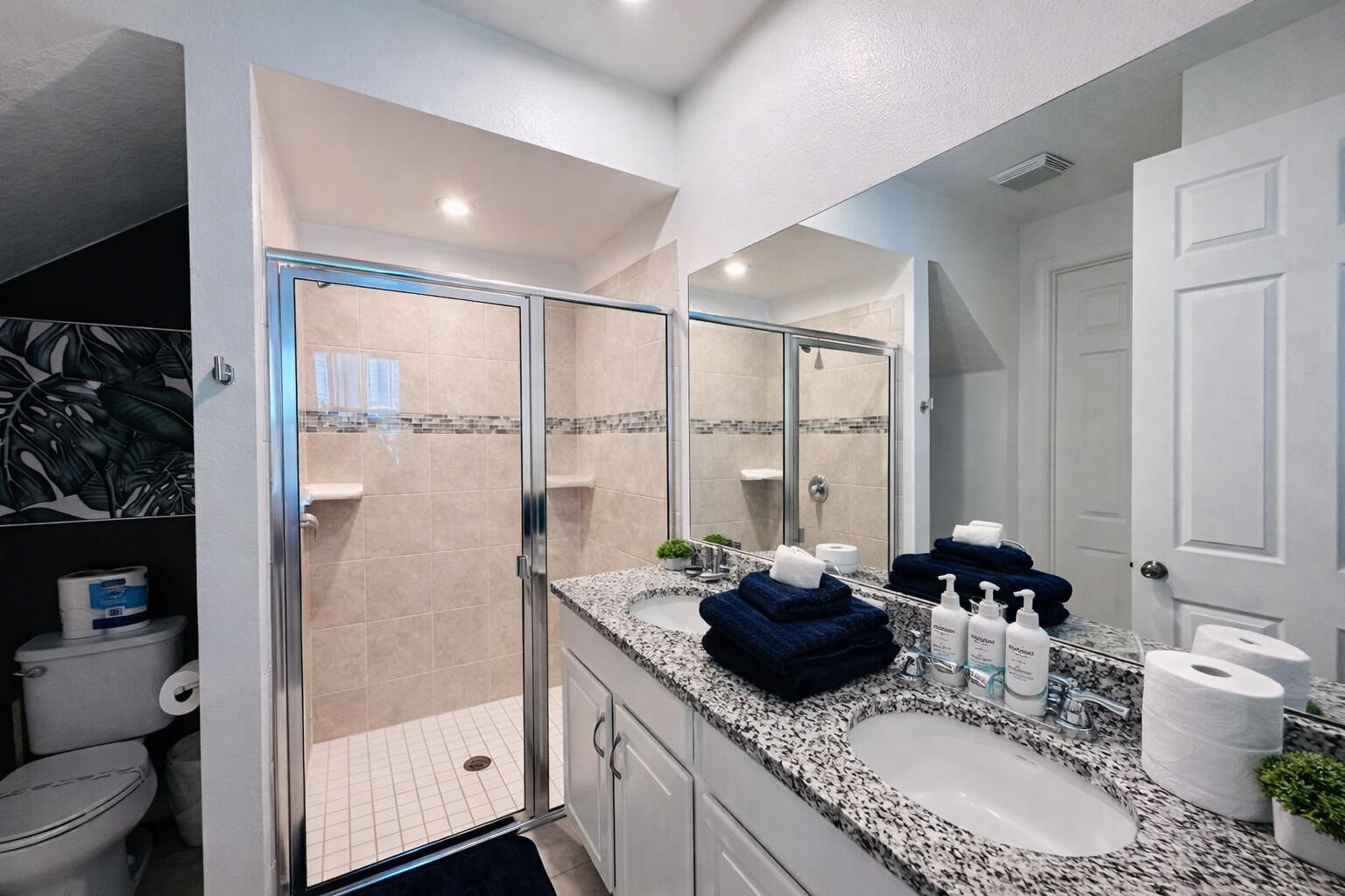 A modern bathroom with a glass-enclosed shower, a double sink vanity, and a large mirror.