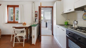 Une cuisine équipée d’une table à manger, de chaises, d’un réfrigérateur, d’une cuisinière et d’une fenêtre avec des rideaux.