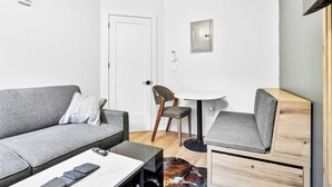 Una sala de estar moderna con un sofá gris, una mesita redonda pequeña, un aparador de madera y una silla.