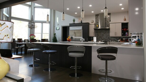 Une cuisine moderne dotée d’un coin bar, de luminaires suspendus et d’une grande fenêtre.