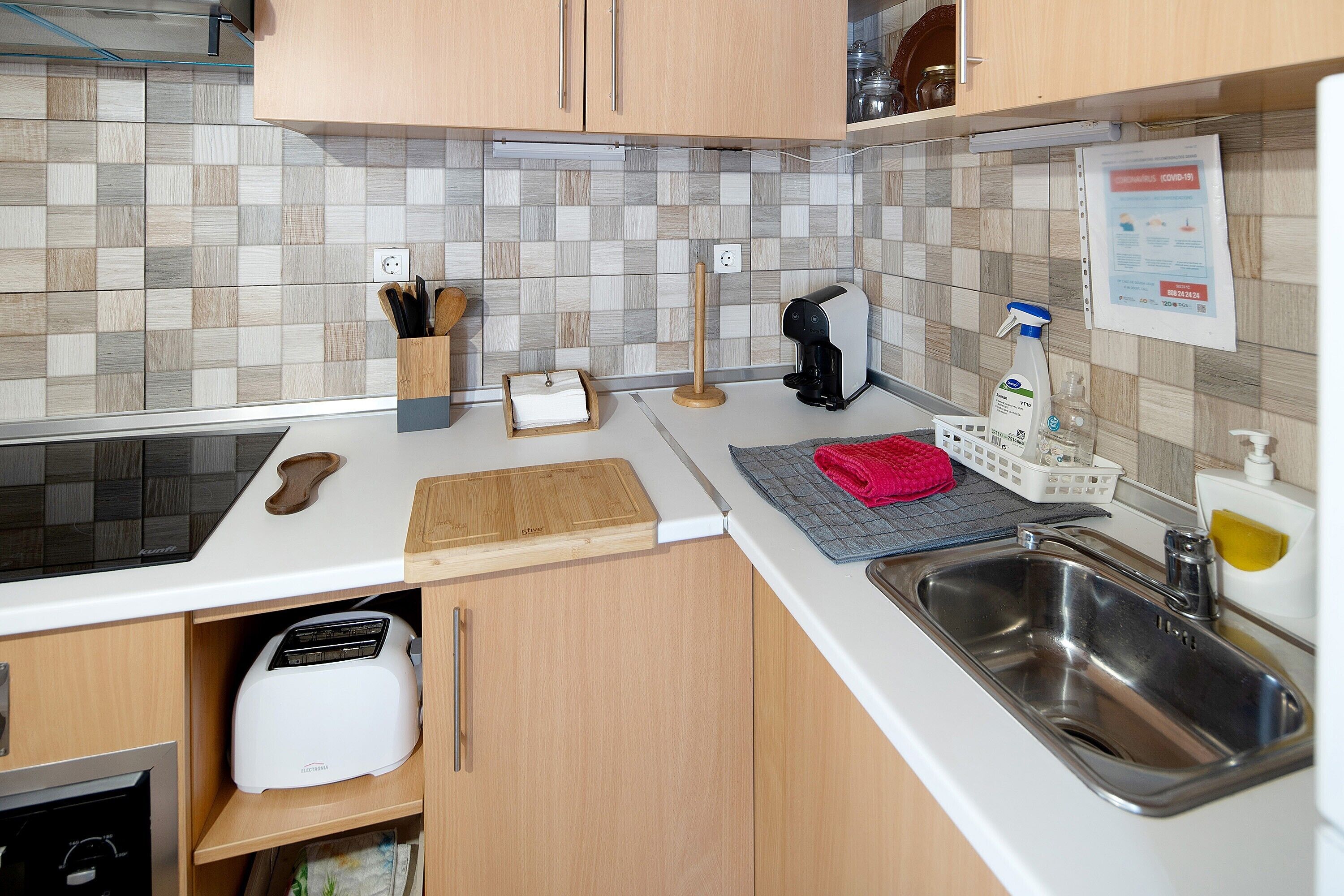 A modern kitchen with a toaster, sink, and a tiled backsplash.