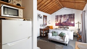 A compact living space with a kitchenette, a bed with a forest-themed wall art, and a dining area. - Studio 'Quinta do Malhinha' with Mountain View, Shared Terrace and Wi-Fi (Posto Santo)
