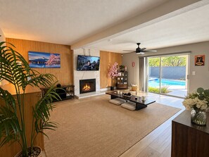A modern living room with a fireplace, television, and a view of a swimming pool. - Tokyo Escape 静 Heated Pool•Spa•Chinatown•Tea Room (Las Vegas)