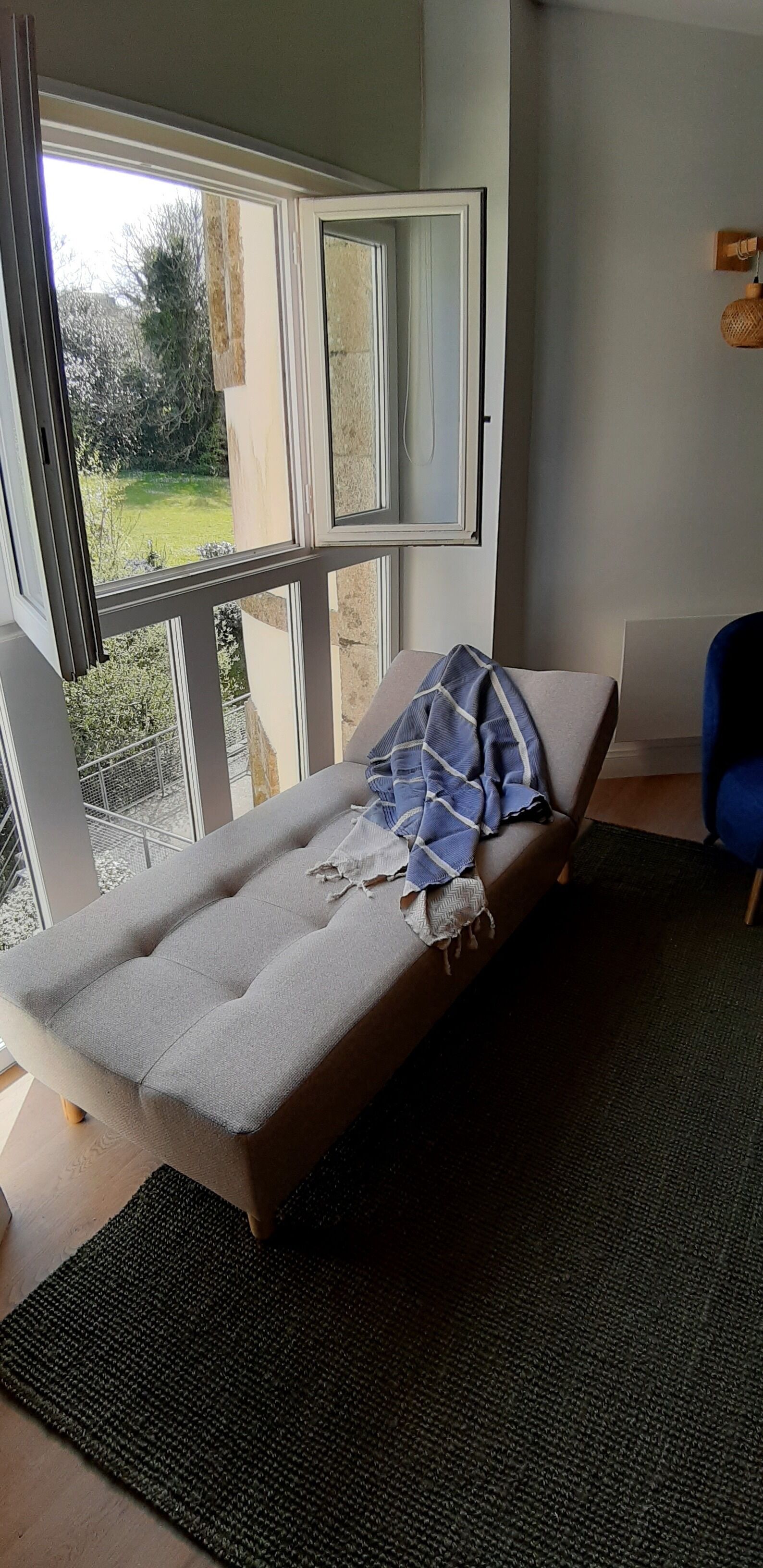 Une pièce avec un lit, une fenêtre, une chaise et une vue sur l’extérieur.