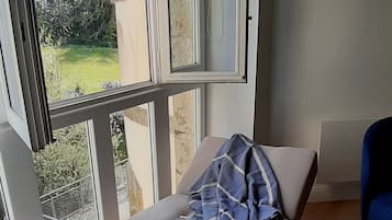 Une pièce avec un lit, une fenêtre, une chaise et une vue sur l’extérieur.