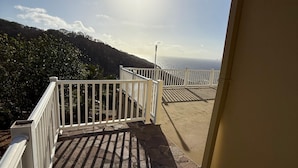 Ein Balkon mit Steinboden, weißen Geländern und Blick auf das Meer.