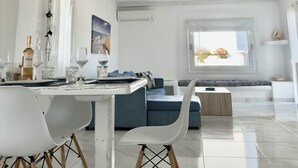 A modern dining area with a white table, chairs, and a wine bottle. - Villa Greystone & Sky Mykonos (Μύκονος)