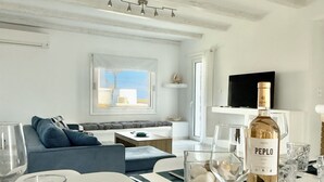 A modern dining area with a table set for two, a bottle of Peppo Rose wine, and a television in the background. - Villa Greystone & Sky Mykonos (Μύκονος)